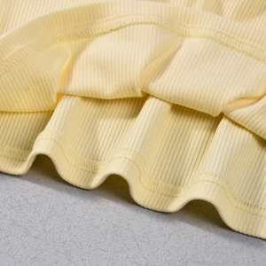 Close-up of light yellow ribbed knit fabric showing detailed hem stitching and texture