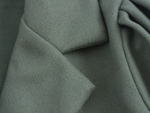 Detail shot of sage green wool coat featuring textured notched lapels and thick fabric