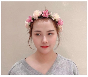 Close-up of pink and cream artificial flower headband worn by a model in soft lighting