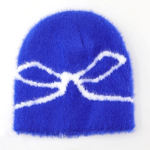 Detail of navy blue fuzzy knit beanie featuring a soft white bow jacquard pattern
