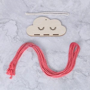 Detailed view of cloud-shaped wooden wall hanging with eyelash design for hair clips