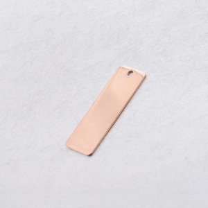 Detailed macro view of a rose gold rectangle metal tag with hole for DIY jewelry making