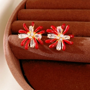 Macro shot of red flower studs with zircon inlay on a dark brown velvet display tray