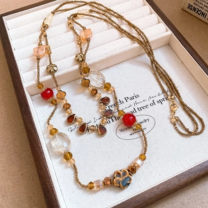 Detail of vintage flower beaded necklace with red and gold accents in a wood jewelry box