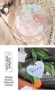 Frosted candy-colored decorative heart and bear charms with golden beaded chains in a glass tray