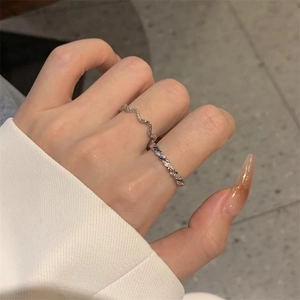 Detail of silver twisted rope and wavy rings set with zircons worn on female fingers