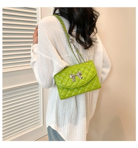 Detail of green quilted bag with silver bow accent and leather chain strap worn by model