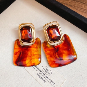 Detail of amber geometric resin earrings with faceted crystal in gold frame