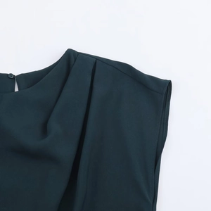 Dettaglio di un top smanicato verde scuro con scollo a pieghe e raffinata trama intrecciata
