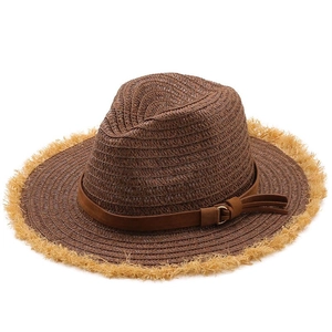 Détail du chapeau en raphia avec bord à franges, ruban en cuir marron et boucle dorée