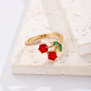 Détail de la bague cerise dorée avec cristaux rouges et feuilles vertes sur pierre blanche