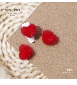 Macro shot of red plush heart nail charms measuring 18mm by 15mm on a woven texture base