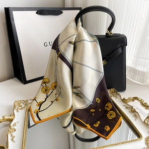 Detail of satin scarf with plum blossom pattern and hand-rolled edges on a designer handbag