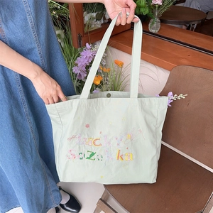 Détails de broderie Lucky Sozakka sur un sac cabas en toile vert menthe à bouton-pression
