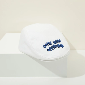 Close-up of blue 3D letter embroidery on a white cotton flat-top beret hat for babies