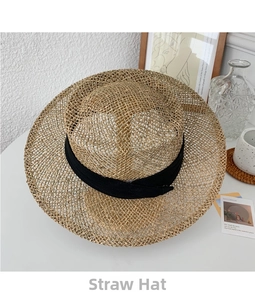 Detailed top view of a wide brim straw sun hat with a black ribbon on a white desk