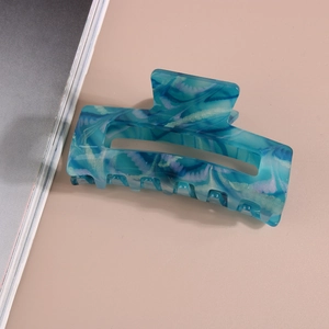 Detail of 8.2cm blue marble acetate hair claw clip with water ripple texture on pink backdrop