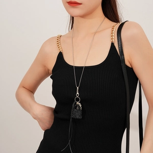 Détail macro du collier argenté avec pendentif sac à main en cristal et franges