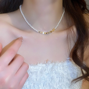 Elegant pearl choker necklace with geometric gold metal accents worn by a model