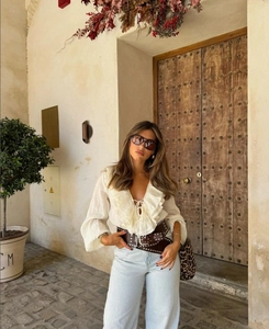 White V-neck ruffle blouse paired with blue wide-leg jeans and a leopard print handbag
