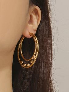 Detail of double-hoop gold earrings with five metallic beads worn by a model