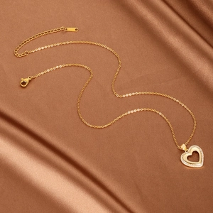 Elegant gold heart necklace with white zircon pavé on luxurious red silk background
