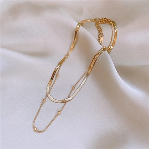 Double-layered gold titanium steel flat snake chain and bead necklace on white silk