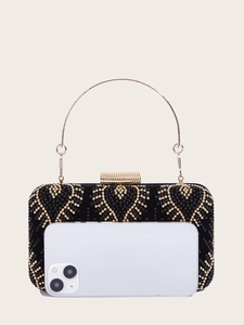 Close-up of black velvet evening clutch with sparkling rhinestone heart pattern and gold handle