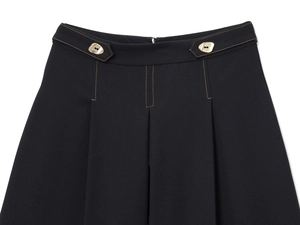 Détail du short noir avec coutures orange contrastées et boutons dorés décoratifs