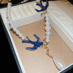 Macro view of pearl necklace with blue swallow accents and clear water drop pendant