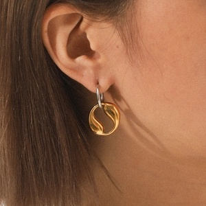 Close-up of geometric two-tone stainless steel hoop earring shown on a model's ear