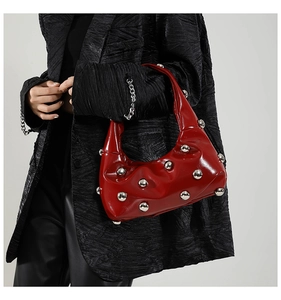 Chic red patent leather crescent bag with silver rivet details worn with black blazer