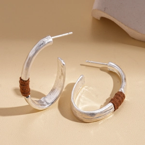 Detail of silver C-shape earrings with hammered texture and brown cord wrapping