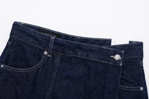 Detailed close-up of dark blue denim skort showing waist button and pocket texture