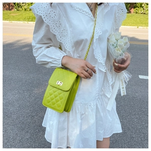 Detail of lime green quilted crossbody bag with gold square metal lock and chain strap