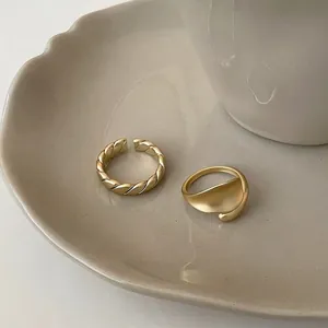 Detail of matte 18K gold plated rings with twisted texture and irregular wave design