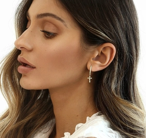 Close-up of gold cross earrings with sparkling zircon stones worn by a model