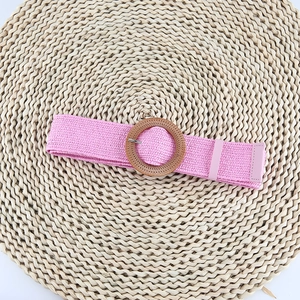 Detailed view of pink woven straw belt with a natural round wooden buckle and leather tip