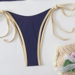 Detail of dark blue bikini bottoms with beige trim, side ties and bead accents