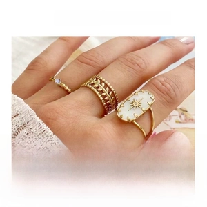 Close-up of three gold-plated stacking rings with laurel leaves and sunburst star motif