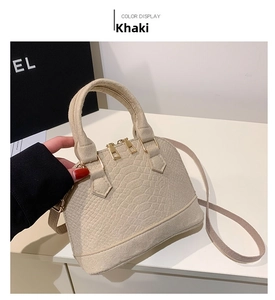 Macro detail of khaki shell bag featuring crocodile-pattern embossed leather and gold hardware