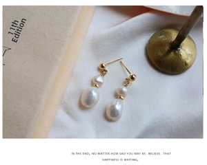 Detail view of vintage French style baroque pearl drop earrings on beige silk fabric