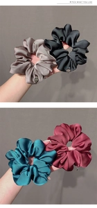 Detail showing four assorted silk satin scrunchies in gray, black, blue and red colors