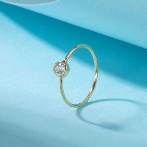 Detail view of a 14K gold minimalist bubble ring with a bezel-set round white gemstone