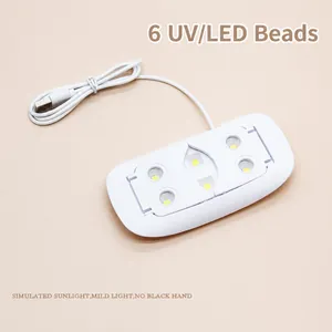 Detail view of mini UV LED nail lamp with 6 beads and foldable stand on pink background