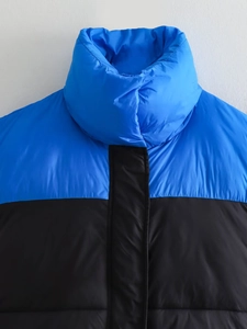 Détail macro du col montant et coutures contrastées bleu et noir sur gilet matelassé