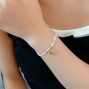 Detailed shot of bohemian beaded bracelet with a gold seashell charm on person wrist