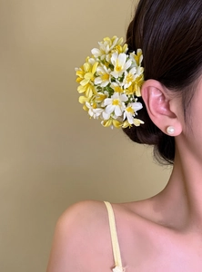 Detailed view of an elegant yellow floral hair clip perfect for beach vacation styles.