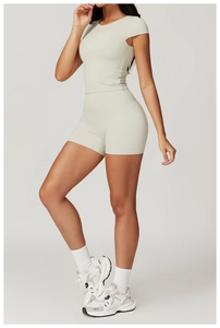 Close-up of beige high-waist sports shorts and fitted short sleeve yoga set on model