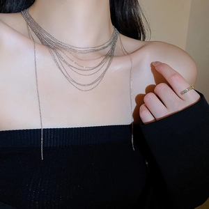 Dettaglio della collana a catena d'argento a strati e anello d'oro con gemma verde